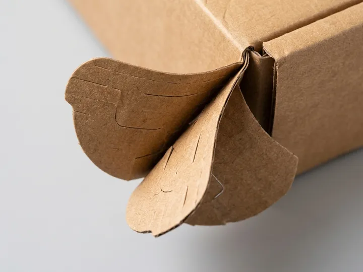 Close-up of layered folding tabs at the self-locking bottom of a recycled corrugated mailer