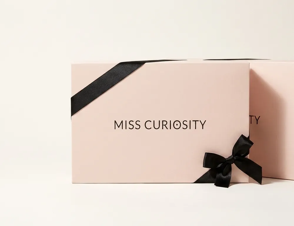 Two pale pink custom bra gift boxes with black satin ribbon bows