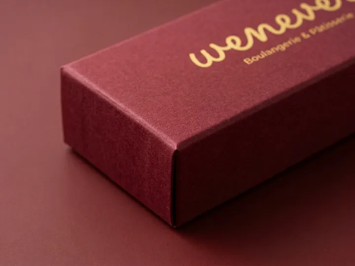 Close view of gold English foil artwork on a matte burgundy chocolate box lid