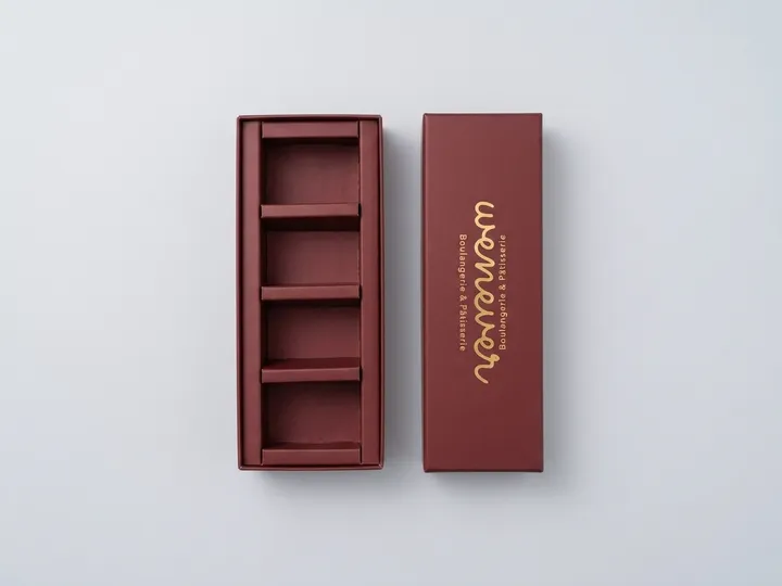 Open burgundy two-piece chocolate box with four chocolates seated in its integrated divider