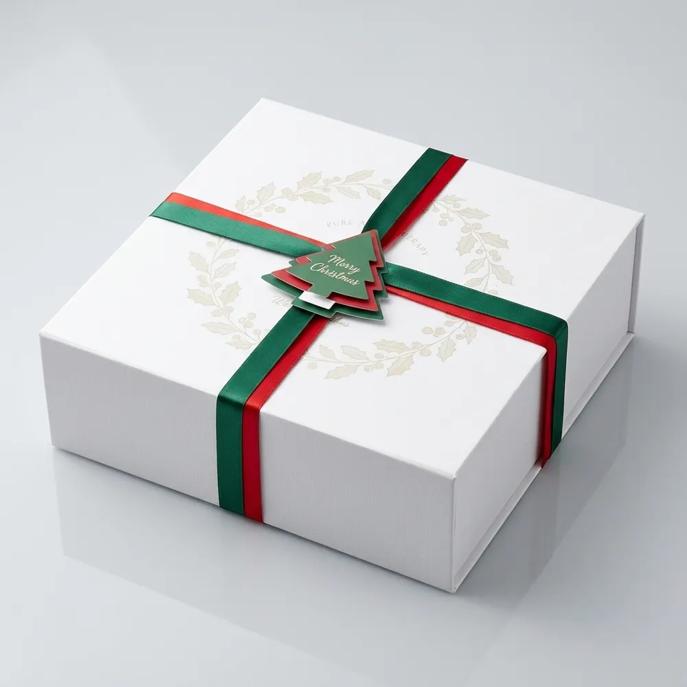 Closed white magnetic Christmas gift box with red and green ribbon and layered tree tag