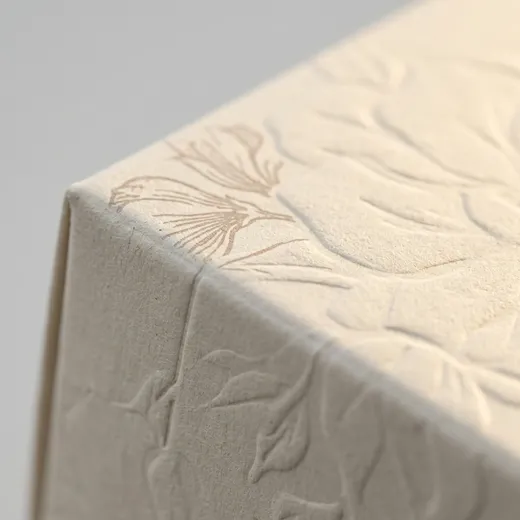 Folded textured paperboard edge with floral embossing