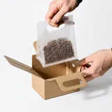 Coffee bean pouch being packed into a kraft paper food and beverage gift box