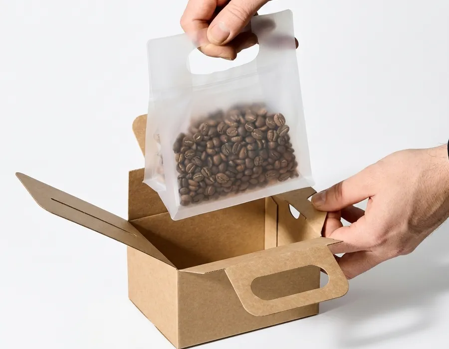 Coffee bean pouch being packed into a kraft paper food and beverage gift box