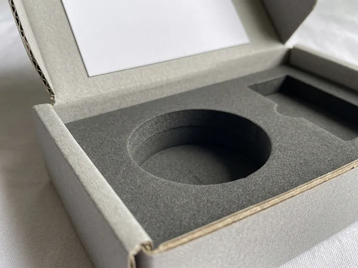 Close-up of a dark gray fitted bottle cavity inside a corrugated perfume mailer box