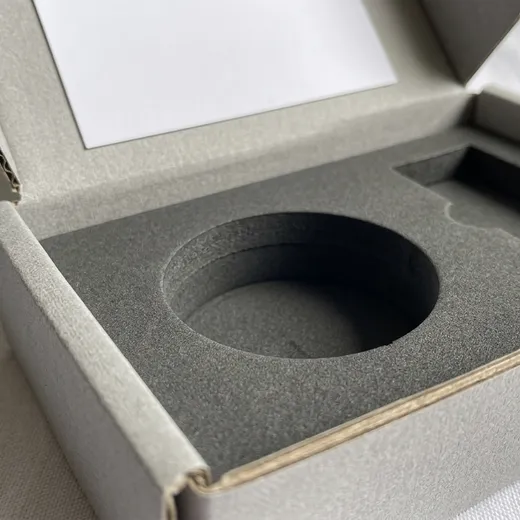 Close-up of a dark gray fitted bottle cavity inside a corrugated perfume mailer box