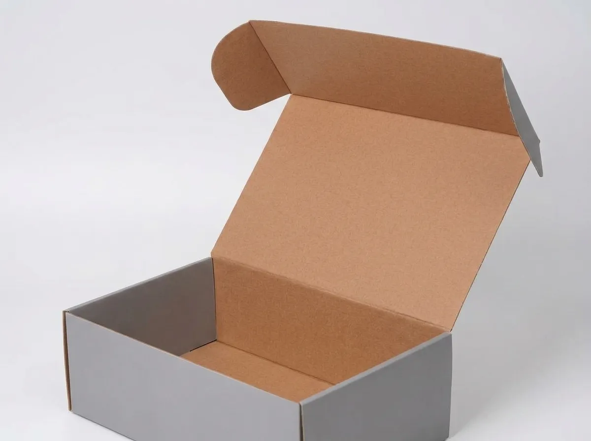Open gray corrugated shoe box showing its hinged lid, natural kraft interior, side walls, and empty base