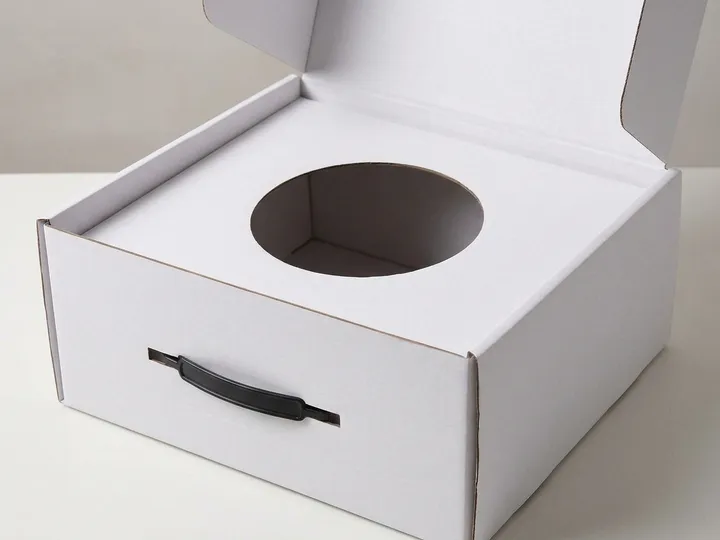 Circular die-cut support opening inside an open white corrugated hat box