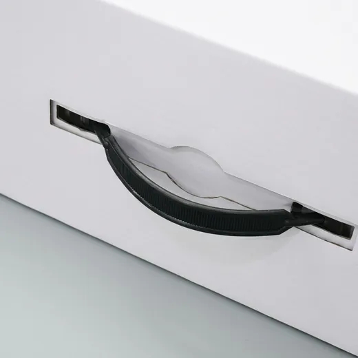 Close-up of a black plastic carry handle mounted through two slots in a white corrugated hat box panel