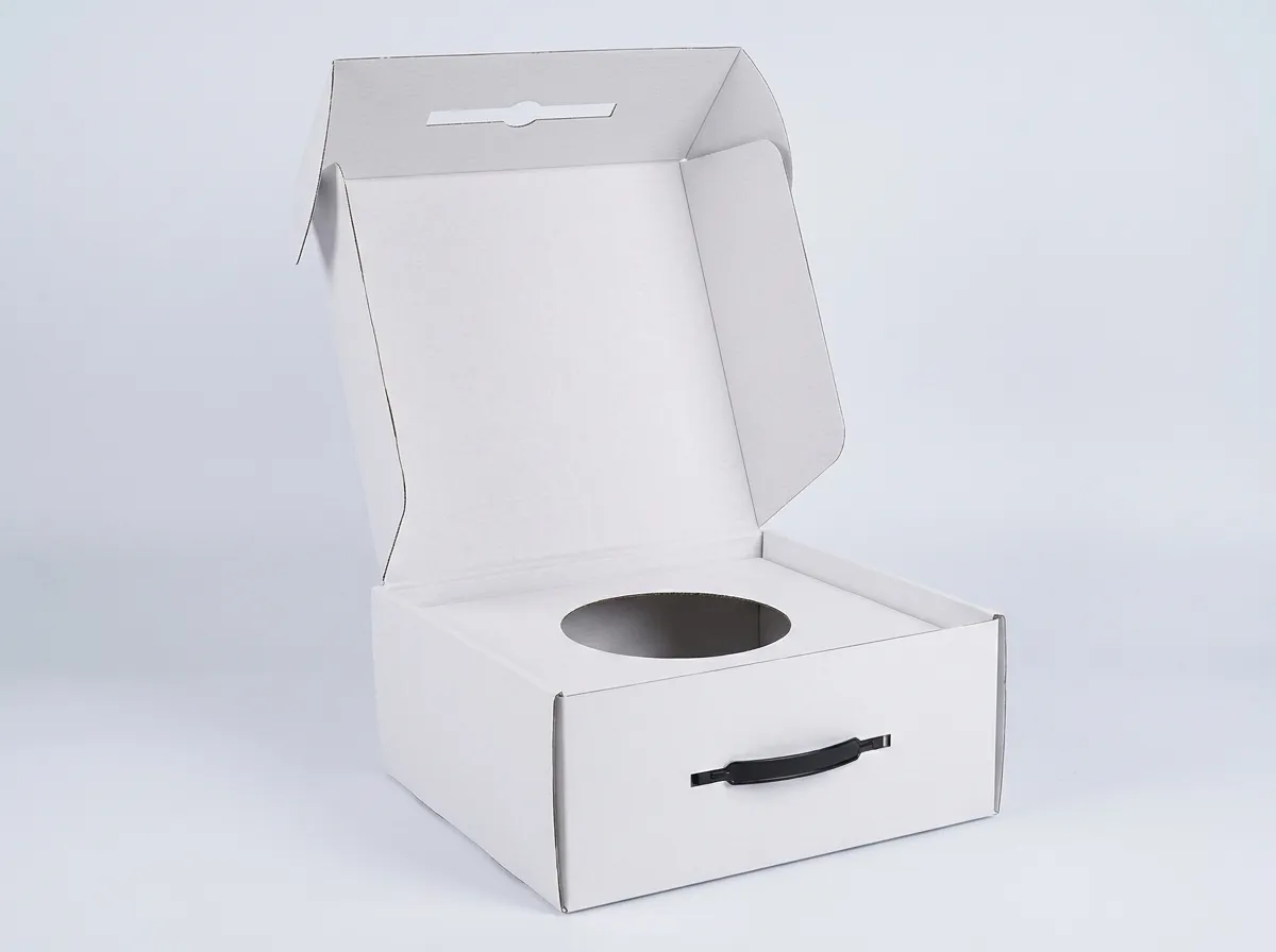 Open white corrugated hat box with hinged lid, side flaps, lid lock slot, circular opening, and black handle
