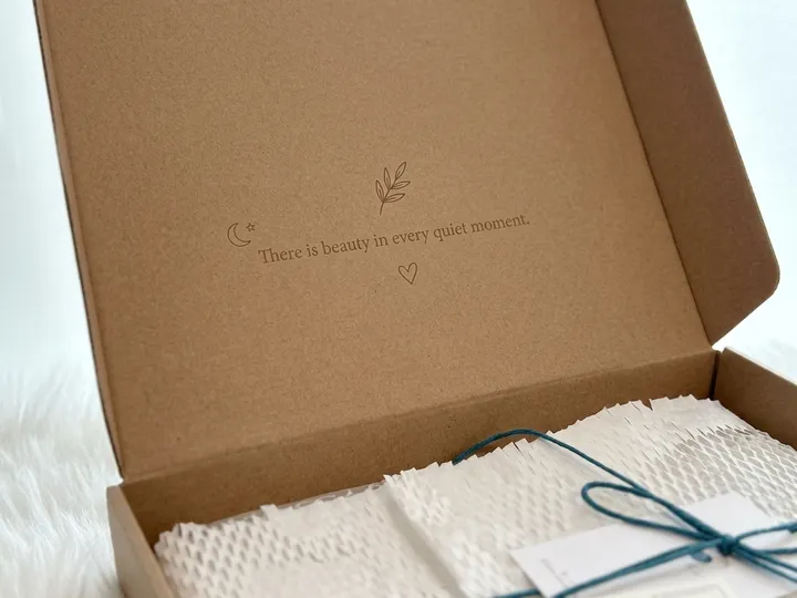 Close view of single-color English sentence and line-art icons printed inside a natural kraft mailer lid