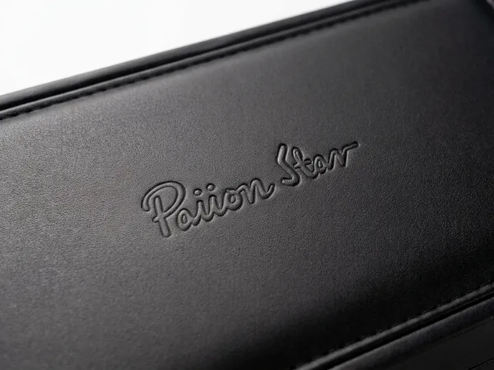Close-up of recessed tone-on-tone logo on fine-grain black PU leather tie box lid