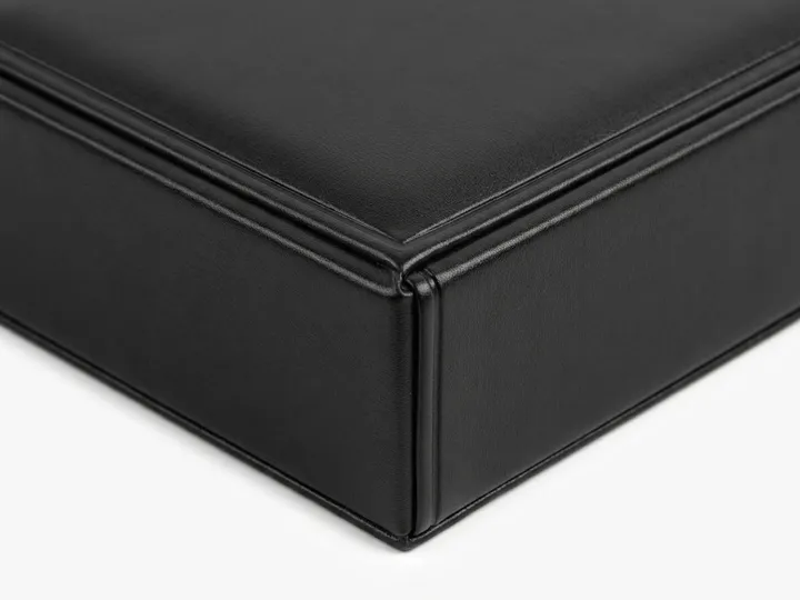 Close-up of wrapped corner and raised edge detailing on a black leather rigid tie box