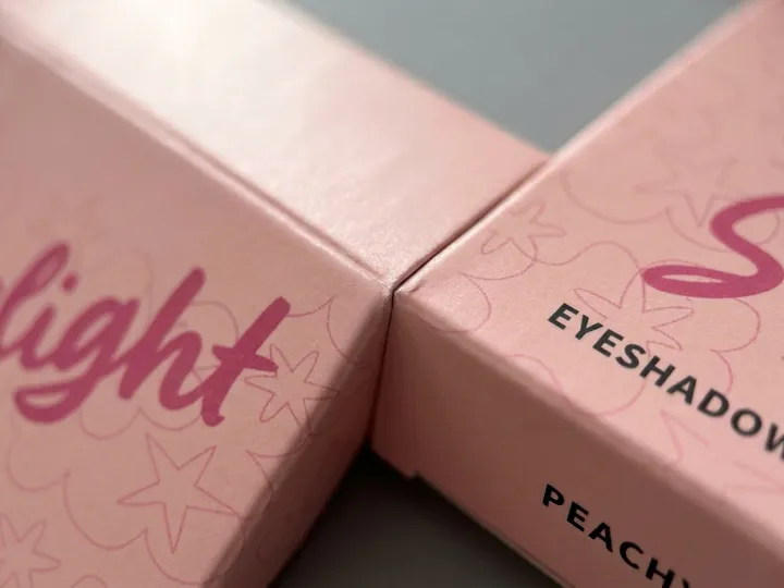 Macro view of pink CMYK artwork and matte lamination across a folded carton edge