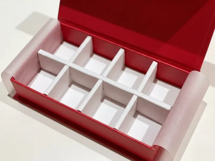 Close view of white divider compartments inside an open red magnetic chocolate gift box