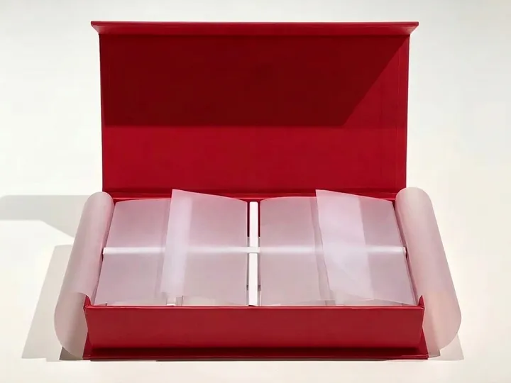 Open red magnetic gift box with white divider walls and translucent glassine side protection