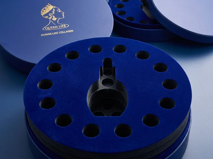Close view of a dark blue flocked EVA insert with one central bottle cavity and surrounding vial cavities