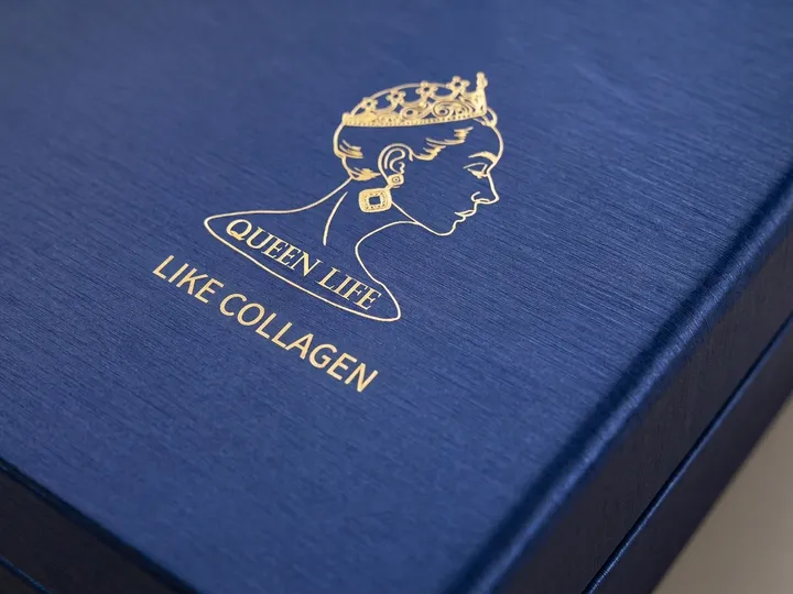 Close view of gold foil artwork on the textured deep blue lid of a round rigid PR box