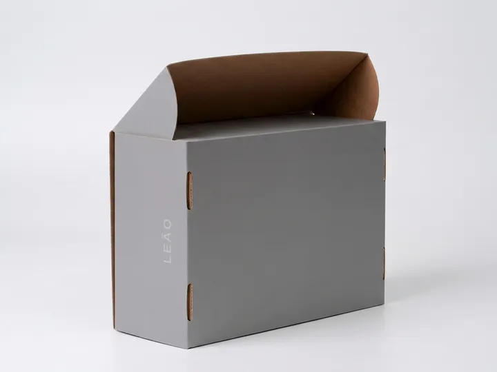 Rear-side view of a gray corrugated shoe box showing elongated self-locking slots and exposed kraft edges