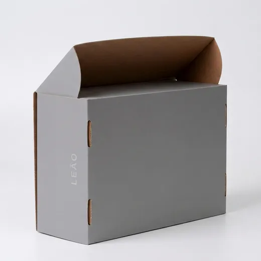 Rear-side view of a gray corrugated shoe box showing elongated self-locking slots and exposed kraft edges