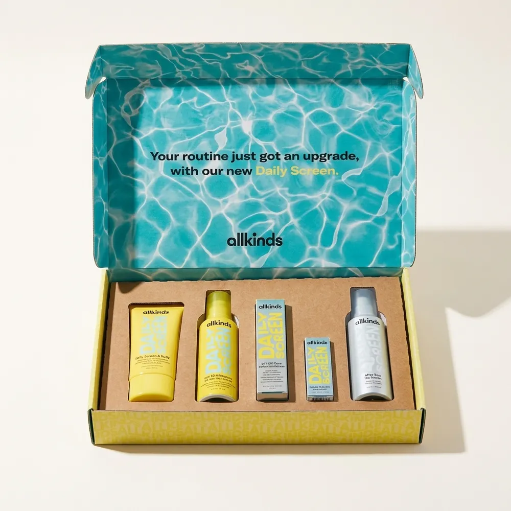 Open custom skincare ecommerce mailer kit with a blue printed lid, yellow exterior, and five products in a corrugated insert
