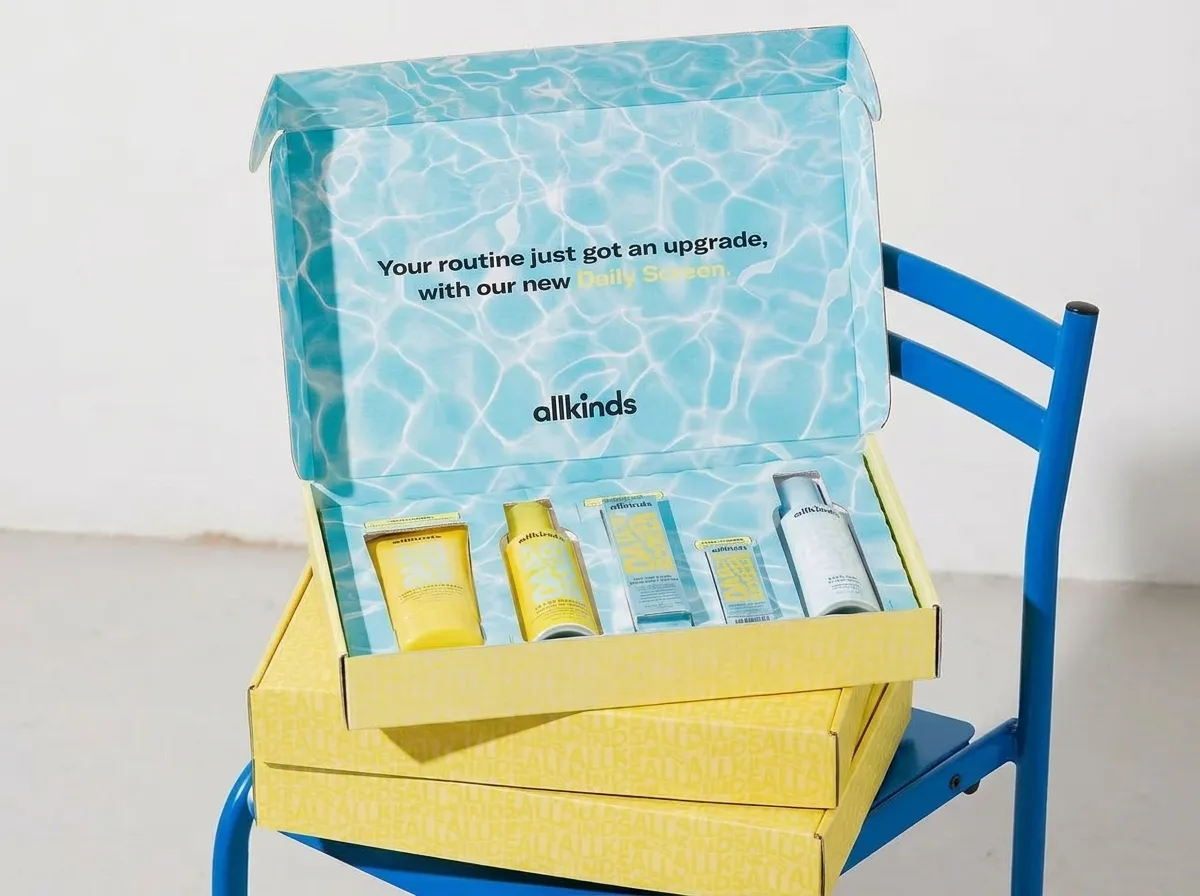 Open yellow skincare ecommerce mailer box showing blue printed lid, side flaps, front wall, and fitted products