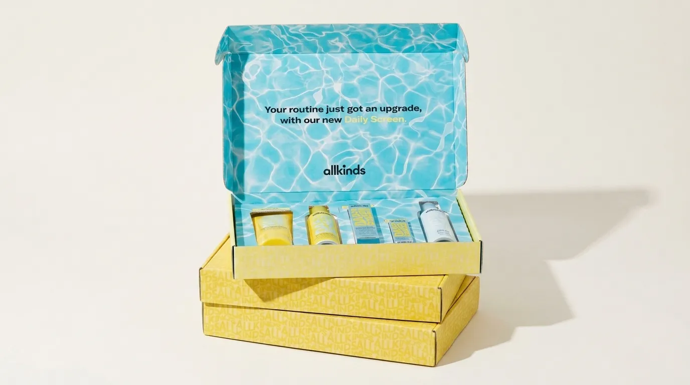 Wide studio view of an open yellow and blue custom skincare ecommerce mailer kit stacked over two closed boxes