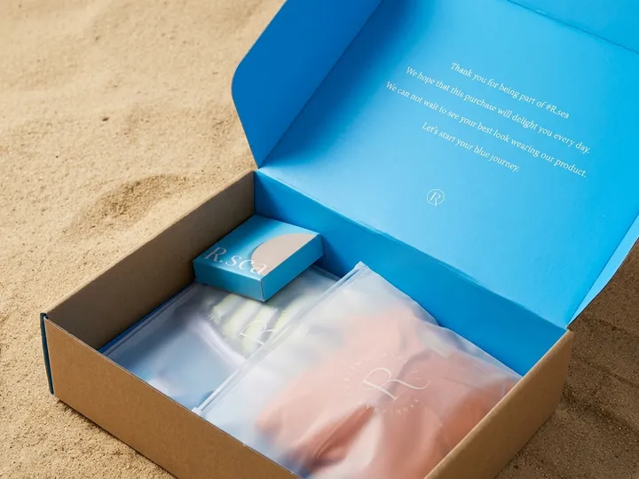 Close view of bright blue inner lid, pale English printing, kraft wall, pouches, and mini carton