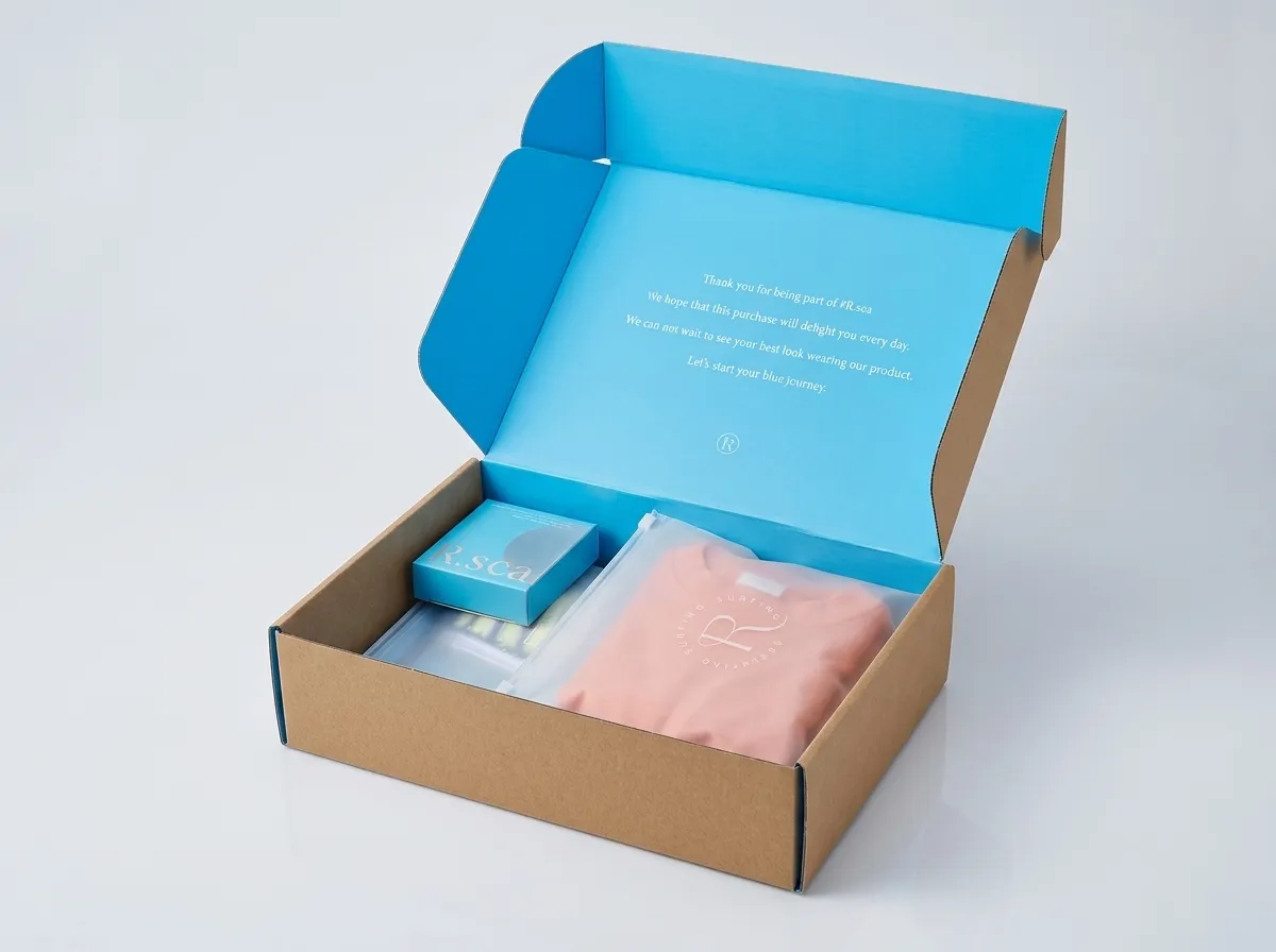 Open kraft swimwear mailer showing blue inner lid, side wings, folded walls, pouches, and accessory box
