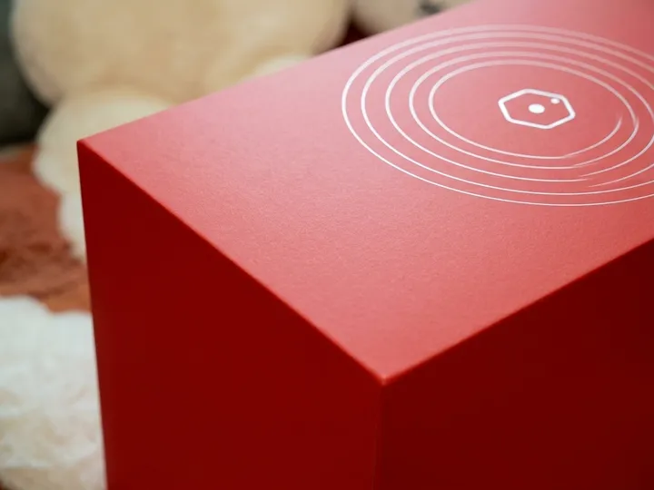 Close view of matte red wrapped paper and white line artwork on a rigid welcome kit lid corner