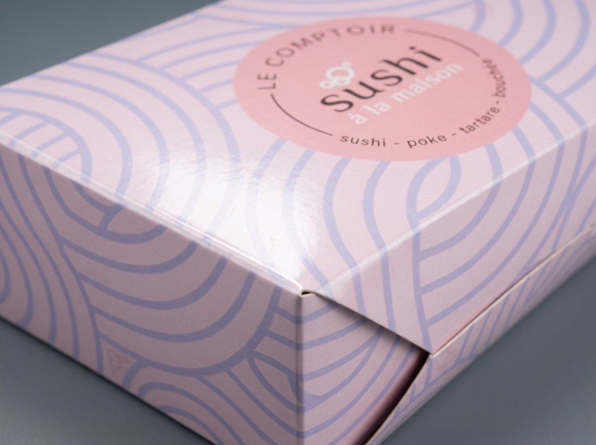 Close view of lavender CMYK wave artwork and a folded edge on a glossy bakery carton