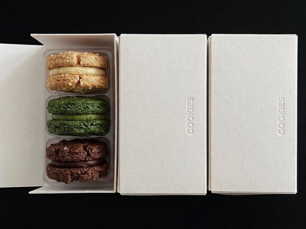 Open custom cookie gift box with a three-cavity tray holding chocolate, matcha, and vanilla sandwich cookies